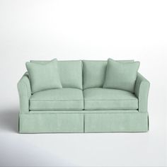 a light green couch with four pillows on it's back and one arm facing the camera