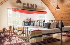 a room with a bed, couch and rugs in the middle of it that has a camp sign on the wall