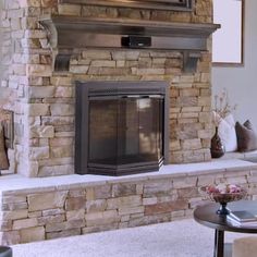 a living room with a stone fireplace and tv above the fire place in the center