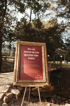 a sign in front of some rocks and trees