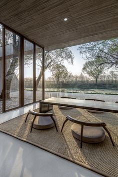 an empty room with chairs and tables in front of large glass windows that look out onto the water