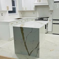 a kitchen with white cabinets and marble counter tops