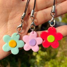 two flower shaped key chains are being held in someone's hand