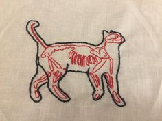 a red and black embroidered cat on a white shirt