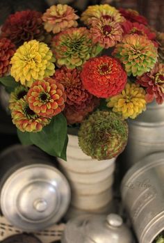 a white vase filled with lots of flowers on top of a table next to canisters