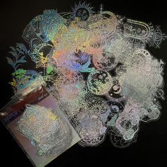 a pile of holographics on a black background with a cup of coffee next to it