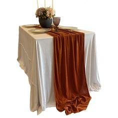 the table is set with two candles and an orange cloth draped over it, along with a vase filled with flowers