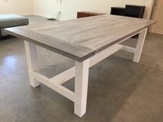 a wooden table with white legs in a room