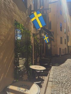 the sun shines on an alleyway with tables and chairs in front of it