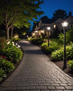 a brick walkway with lights on and flowers in the foreground