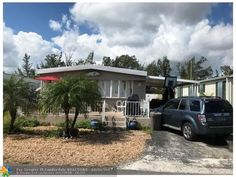 a house with a car parked in front of it next to a tree and bushes