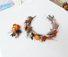 two wreaths made out of dried flowers and leaves on a white tablecloth with other items in the background