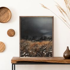 three wooden plates on a shelf next to a painting and vase with dried grass in it