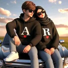 two people sitting on the hood of a car wearing matching sweatshirts with letters and hearts