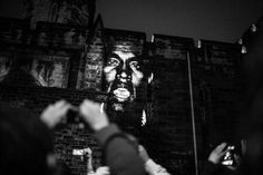 black and white photograph of a man's face on the side of a brick wall