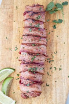 sliced meat on a cutting board with limes and cilantro