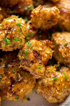 a plate full of fried meatballs with parsley on top and seasoning sprigs