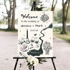 a welcome sign for a wedding with flowers on the ground and trees in the background