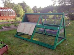 a green chicken coop sitting on top of a lush green field