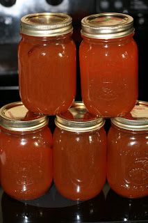 several jars filled with red liquid sitting on top of a black table next to an oven