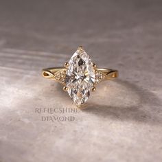 a yellow gold engagement ring with a pear shaped diamond in the center and side stones