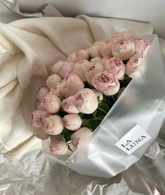 a bouquet of pink flowers sitting on top of a white sheet