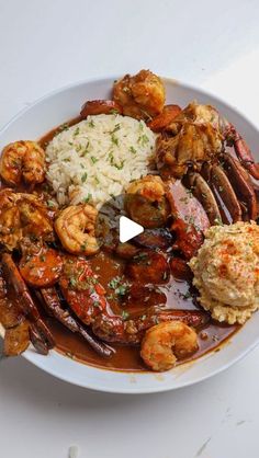 a white plate topped with meat and shrimp covered in gravy next to rice