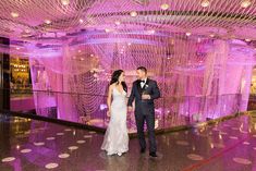 a bride and groom are standing in front of a pink backdrop at their wedding reception