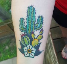 a small cactus tattoo on the left leg with flowers and leaves in it's center