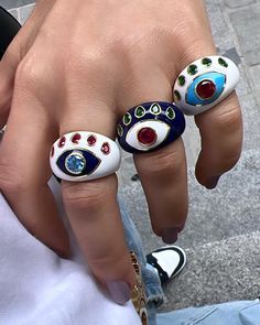 a person with three different rings on their fingers and one has an evil eye ring