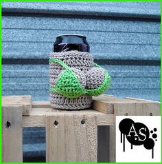 a crocheted coffee cup cozyie sitting on top of a wooden fence post