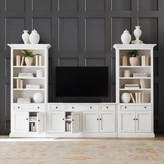 a white entertainment center with bookshelves and vases