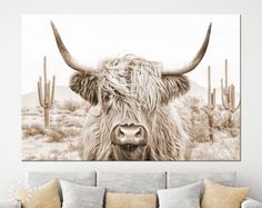 a cow with long horns standing in front of some cactus trees and desert scenery, black and white photograph