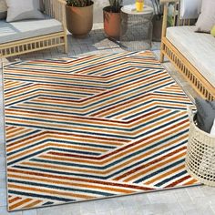 a colorful area rug on a patio with chairs and potted plants in the background