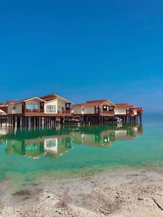 several houses on stilts in the water with clear blue skies