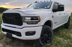 a white ram truck parked on top of a grass covered field