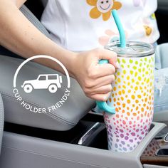 a woman holding a cup in her hand while sitting in the back seat of a car