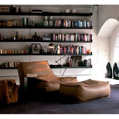 a living room filled with furniture and bookshelves next to a wall mounted book shelf