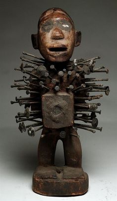 an old wooden statue with lots of metal parts on it's face and arms