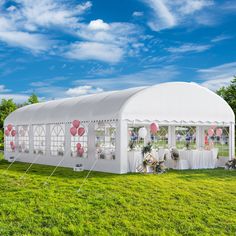 a large white tent set up in the middle of a field with balloons on it