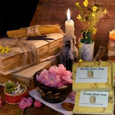 a table topped with flowers and candles next to some books on top of a wooden table