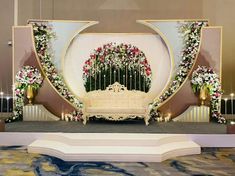 a stage set up for a wedding ceremony with flowers and candles on the side wall