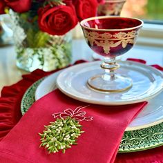 a table with red roses in vases and place settings on the plates, along with napkins