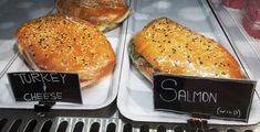 two trays filled with sandwiches sitting on top of a counter next to each other