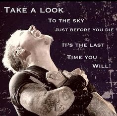 a man with tattoos and piercings is looking up into the sky while holding his hands to his chest