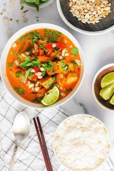 three bowls of food on a table with chopsticks and spoons next to them