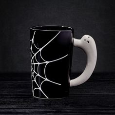 a black and white coffee mug with a spider web design on the outside of it