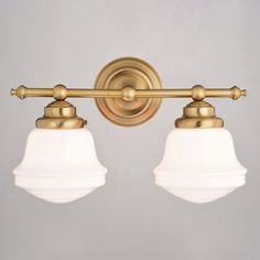 two light bathroom fixture with white glass shades on the top and gold trimmings