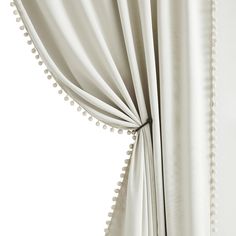 a white curtain with pom poms hanging from it's side and the curtains are closed