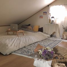 a bed with white sheets and pillows in a loft room next to a laptop computer